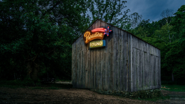 The Paradise Found neon sign on the small barn at the Coler Homestead in the dark